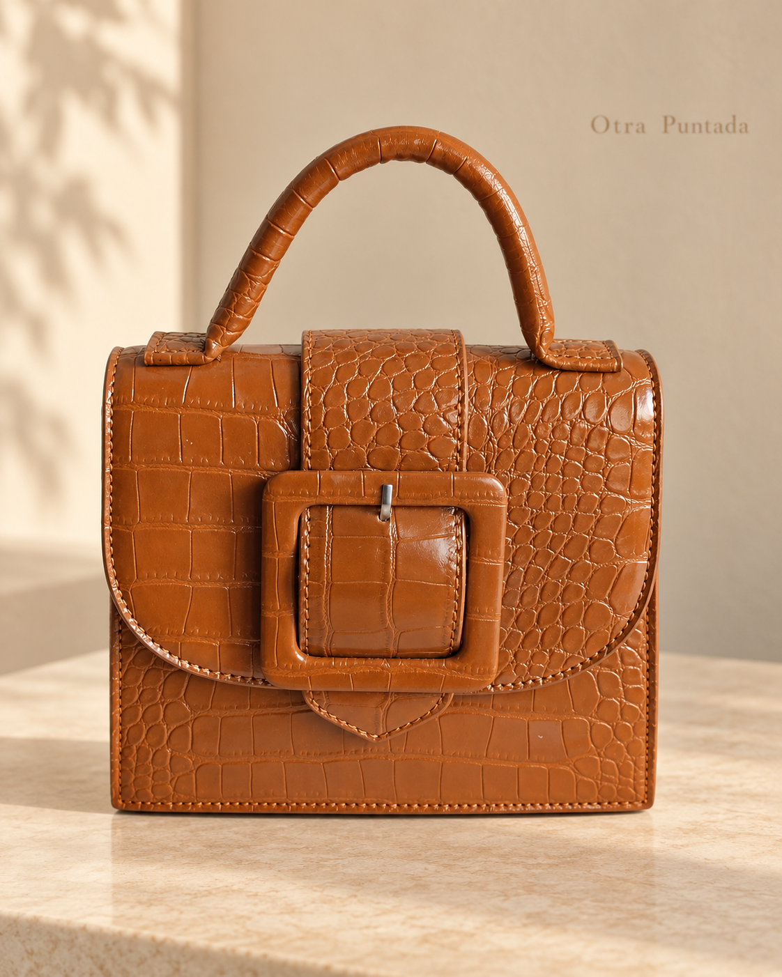 Bolso Mara color coñac con textura efecto cocodrilo y hebilla frontal.
