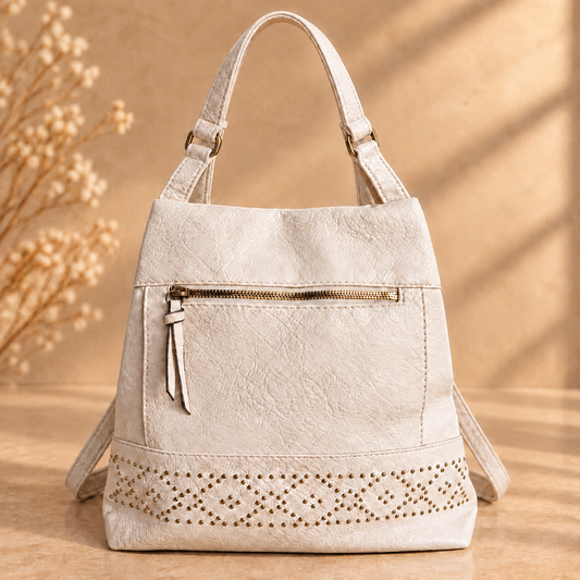 Mochila Nara color crema, con asa superior y tachuelas en la parte inferior.